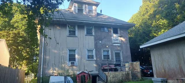 a front view of a house with outdoor seating and covered with trees