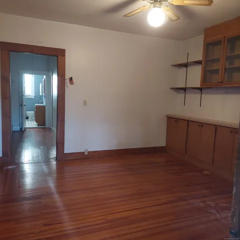 a view of an empty room with wooden floor and a chandelier