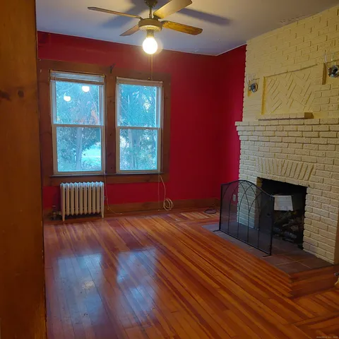 a view of a livingroom with wooden floor and a fireplace