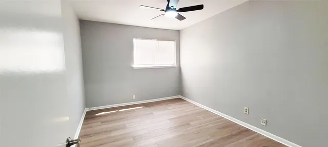 an empty room with a window and a ceiling fan