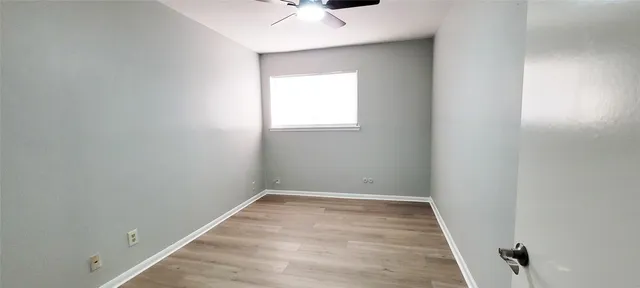 an empty room with a window and a ceiling fan