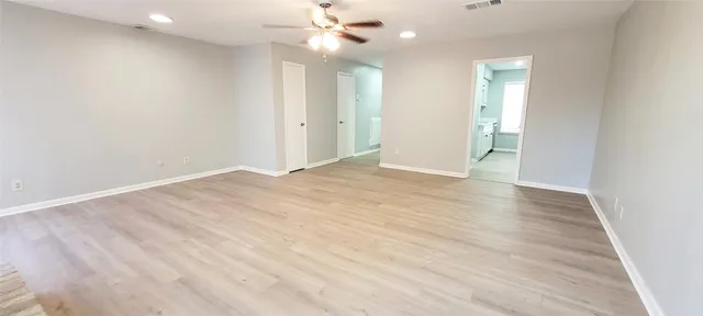 an empty room with wooden floor and fan