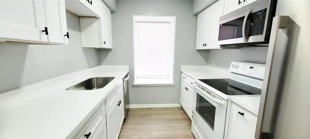 a kitchen with a sink a microwave and cabinets