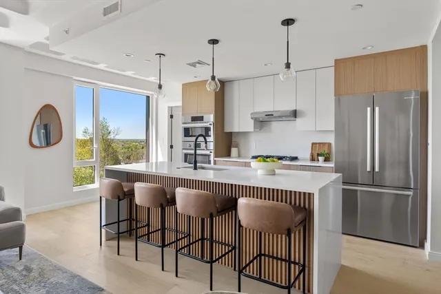 a kitchen with stainless steel appliances granite countertop a dining table chairs refrigerator and cabinets