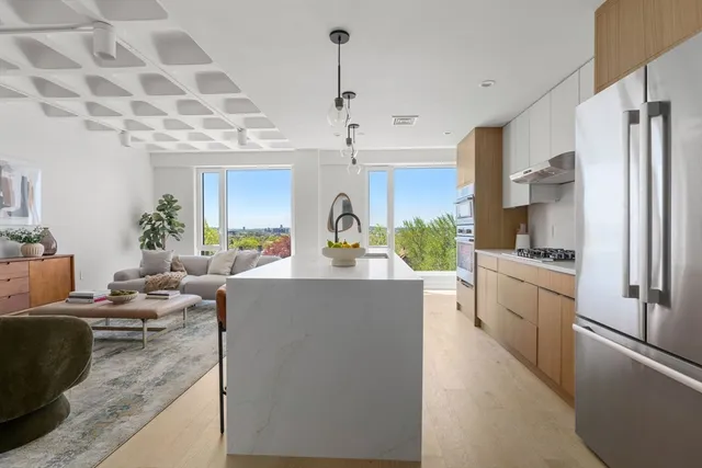 a large kitchen with kitchen island a counter top space a sink stainless steel appliances and cabinets