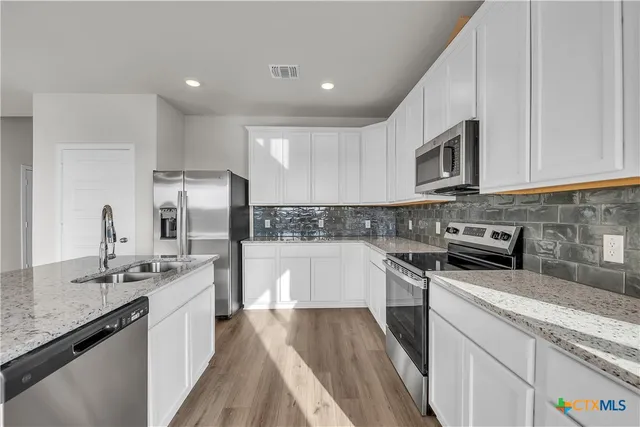 a kitchen with stainless steel appliances granite countertop a sink stove and refrigerator
