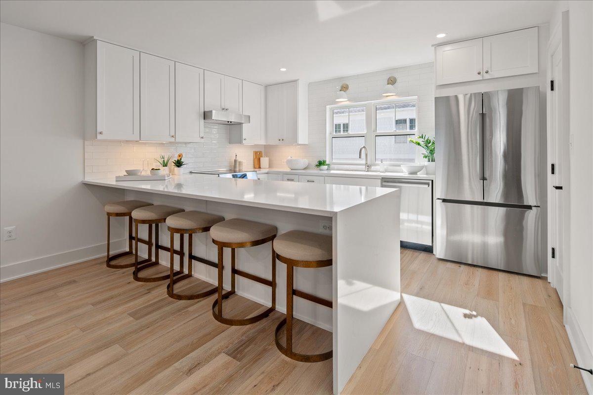 909 North Irving Street Arlington, VA 22201 - Photo 24 of 69 a kitchen with stainless steel appliances a sink a stove a refrigerator and white cabinets with wooden floor