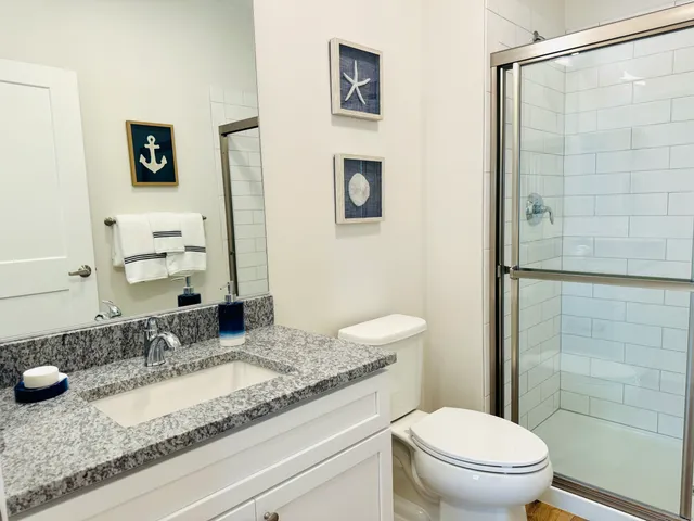 a bathroom with a granite countertop shower a toilet and a sink