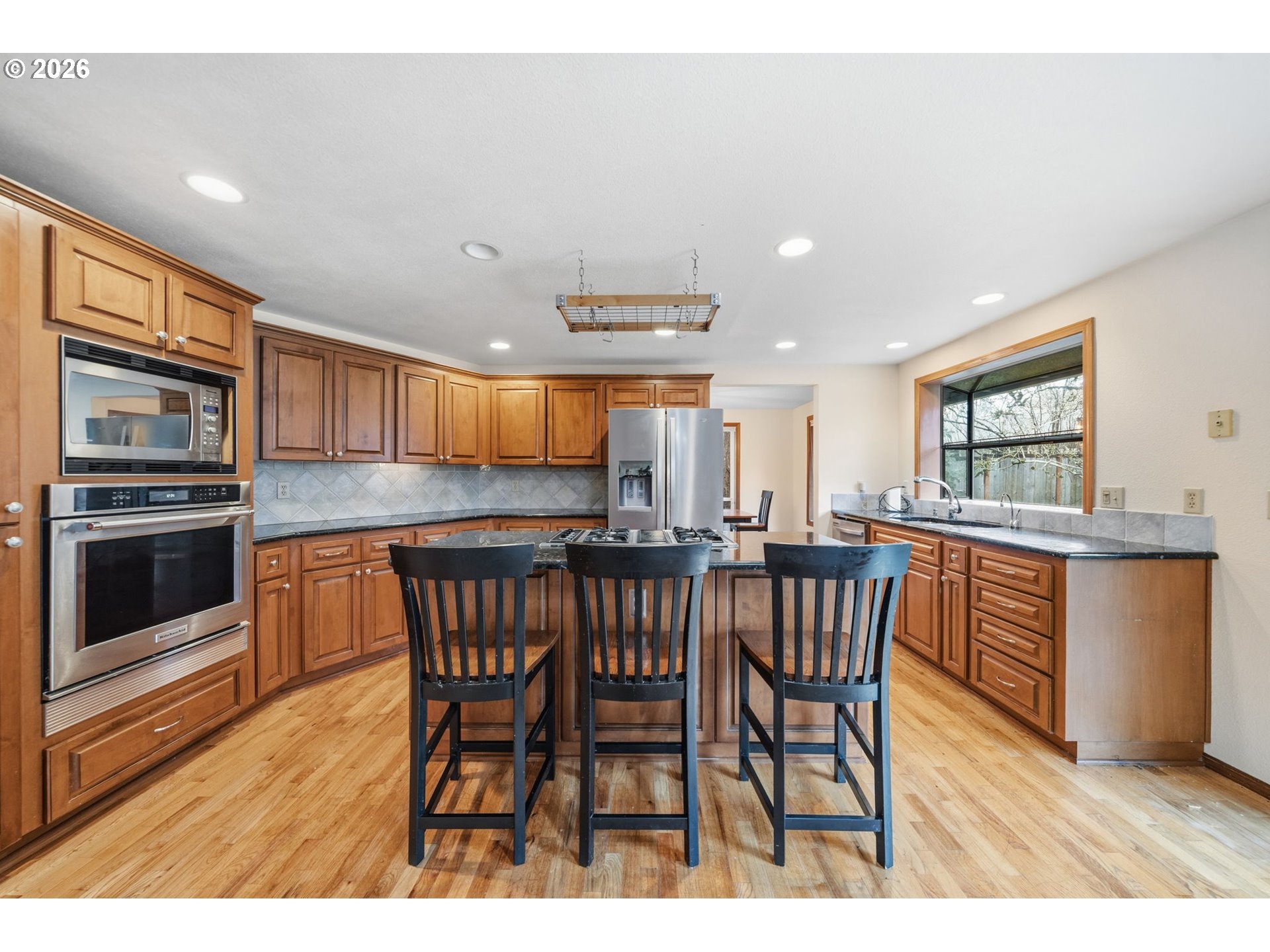 13825 Southwest Weir Road Beaverton, OR 97008 - Photo 9 of 40 a kitchen with stainless steel appliances granite countertop a kitchen island hardwood floor and a sink
