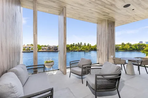 a view of swimming pool with lawn chairs plants and palm trees
