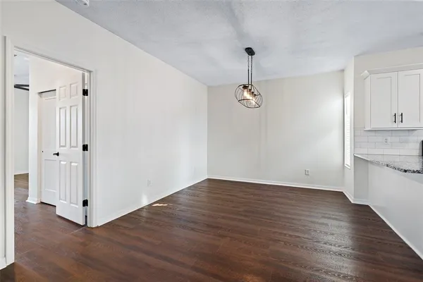 a kitchen with stainless steel appliances granite countertop a refrigerator a sink dishwasher a stove and white countertops with wooden floor