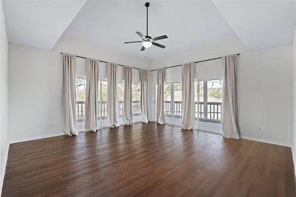 a view of an empty room with wooden floor and window