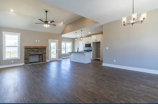 an empty room with wooden floor fireplace and windows