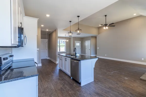a kitchen with granite countertop a stove a sink and a refrigerator