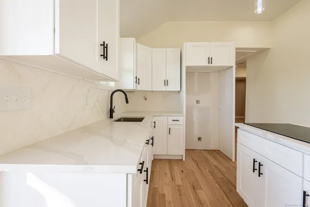 a kitchen with a stove a refrigerator and white cabinets with wooden floor