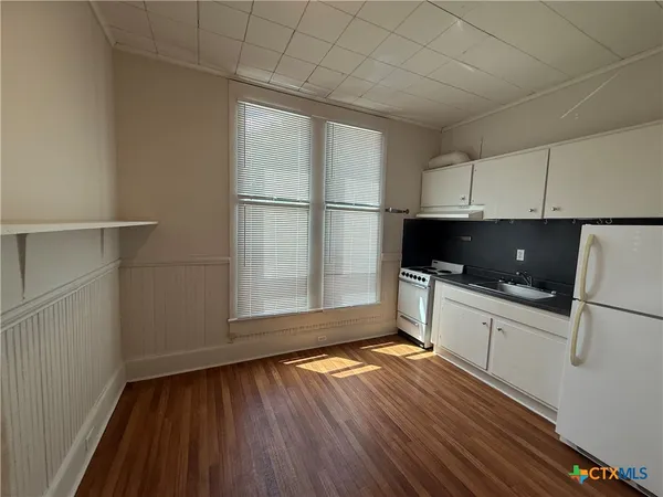 a view of a room with wooden floor and electronic appliances