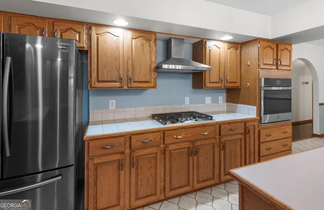 a kitchen with stainless steel appliances granite countertop a refrigerator a sink dishwasher and wooden cabinets with wooden floor