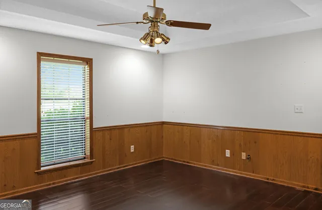 a view of empty room with wooden floor and fan