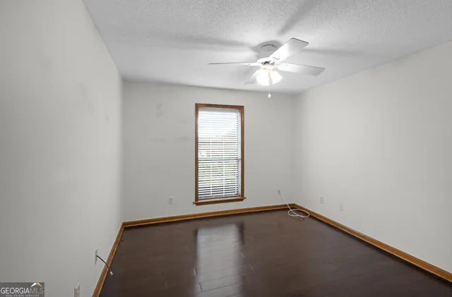an empty room with wooden floor closet ceiling fan and window
