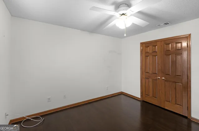 an empty room with windows and fan