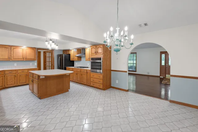 a view of a kitchen with kitchen island granite countertop a refrigerator and a stove top oven