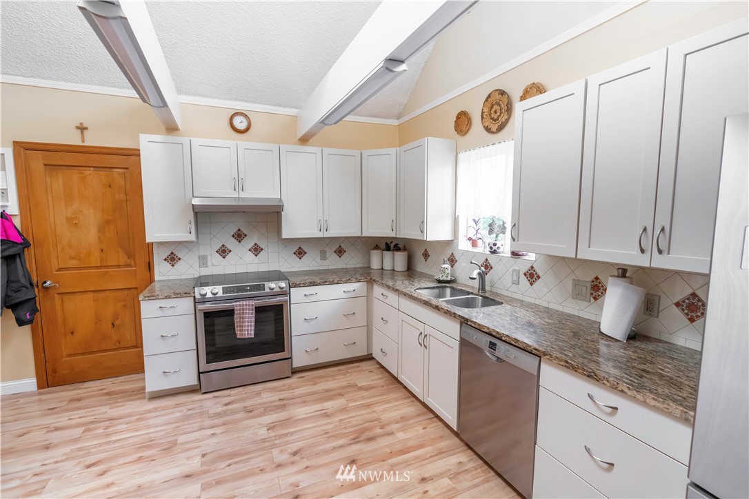 6502 Avondale Road Southwest, Unit 4 Lakewood, WA 98499 - Photo 11 of 28 a kitchen with granite countertop a sink stainless steel appliances and cabinets