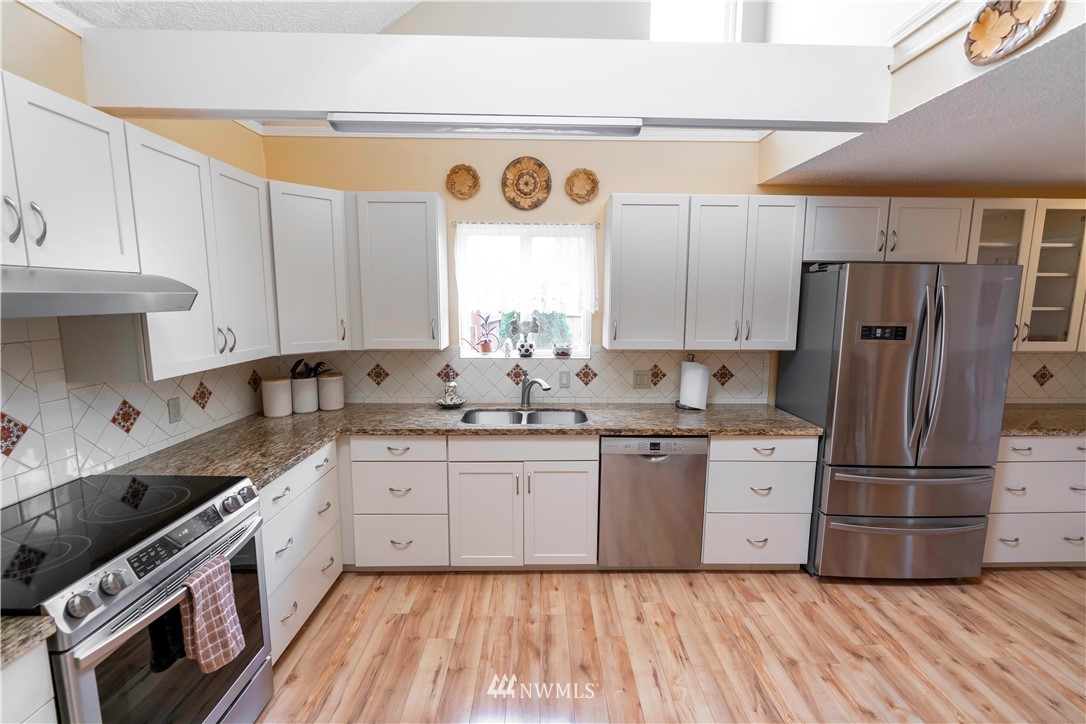6502 Avondale Road Southwest, Unit 4 Lakewood, WA 98499 - Photo 10 of 28 a large kitchen with granite countertop a stove top oven a sink and a refrigerator