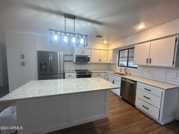 a large kitchen with granite countertop a sink a center island and stainless steel appliances
