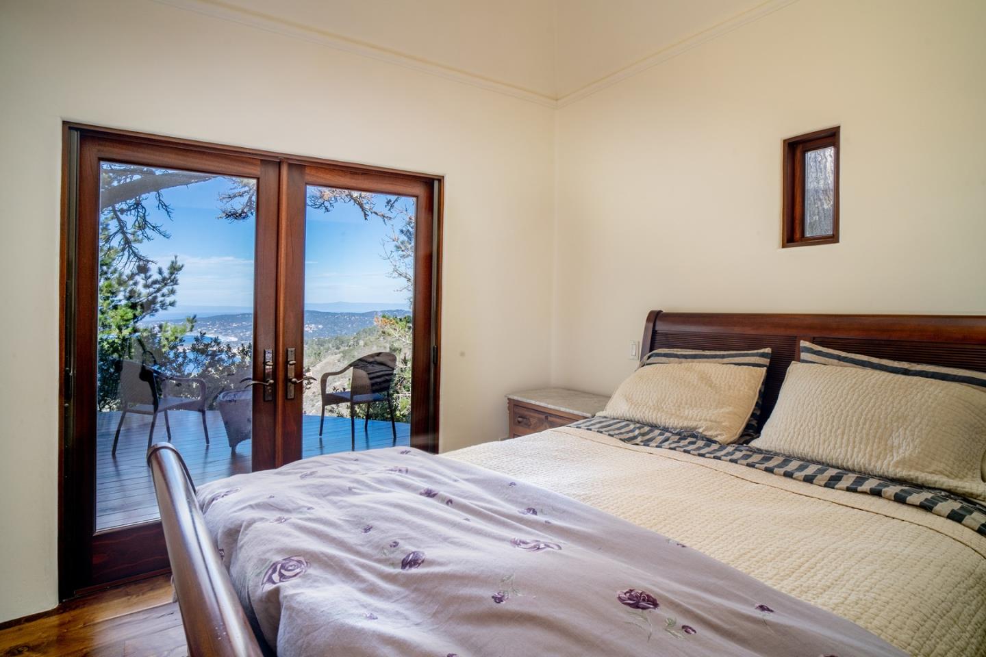309 Mt Devon Road Carmel, CA 93923 - Photo 28 of 32 a bedroom with a bed and a large mirror next to a large window with wooden floor