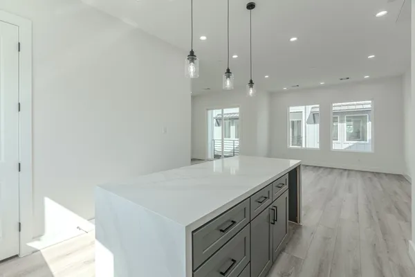 a kitchen with a sink chandelier and wooden floor