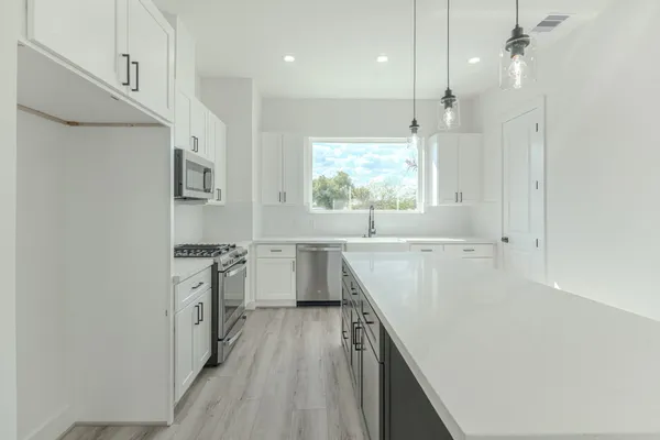a view of kitchen with stainless steel appliances cabinets and a window