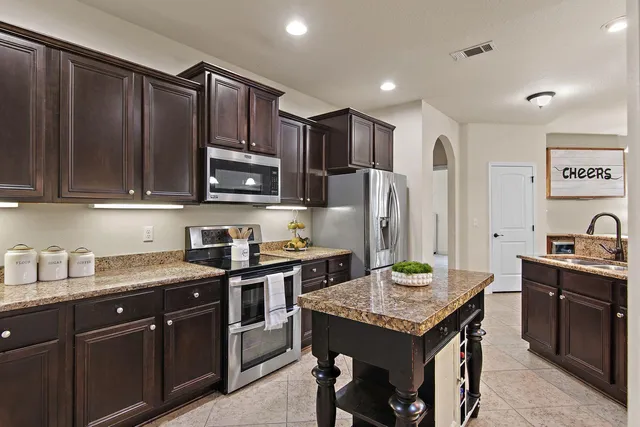 a kitchen with granite countertop stainless steel appliances a stove refrigerator sink and microwave