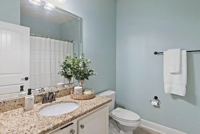 a bathroom with a granite countertop sink a mirror and a toilet