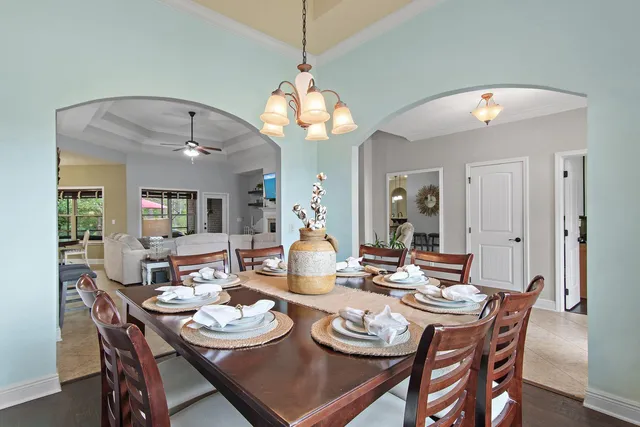 a dining room with wooden floor a chandelier a wooden table and chairs