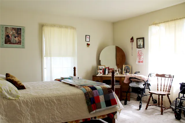 a bedroom with a bed a dresser and chair