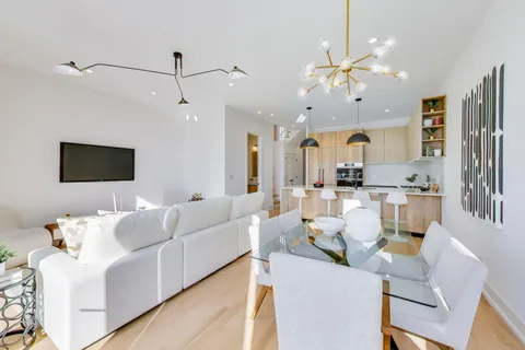 a living room with furniture kitchen view and a chandelier