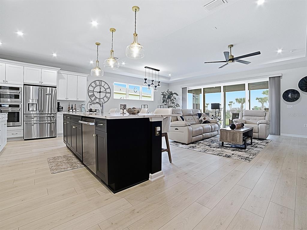 1599 Bellagio Loop Tavares, FL 32778 - Photo 6 of 75 a living room with stainless steel appliances kitchen island granite countertop lots of wooden furniture a sink a stove and a refrigerator