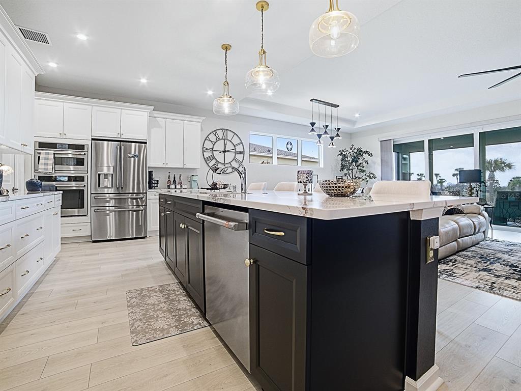 1599 Bellagio Loop Tavares, FL 32778 - Photo 8 of 75 a kitchen with counter top space cabinets a sink stainless steel appliances and a chandelier