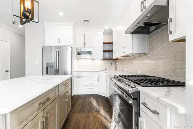 a kitchen with stainless steel appliances kitchen island a stove a refrigerator and a sink