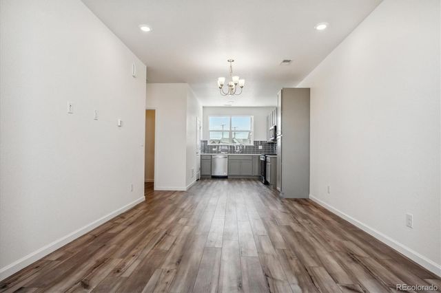 a view of a kitchen with a sink and dishwasher a refrigerator with wooden floor