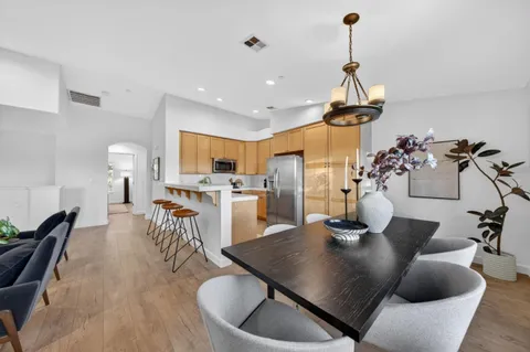 a kitchen with stainless steel appliances granite countertop a sink dishwasher a refrigerator white cabinets and couches with wooden floor