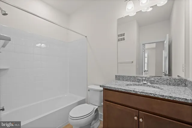 a bathroom with a granite countertop sink a toilet and shower