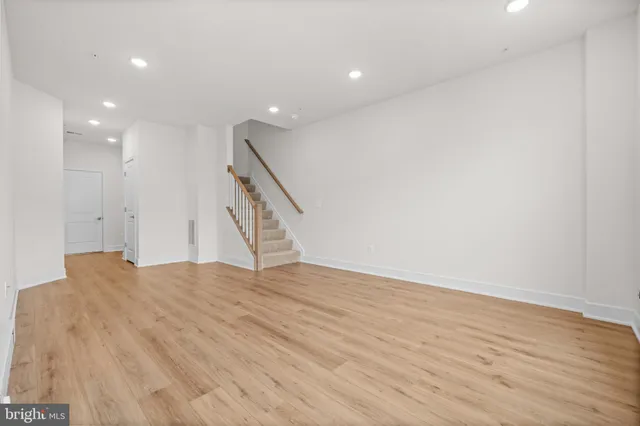 a view of an empty room with wooden floor and stairs