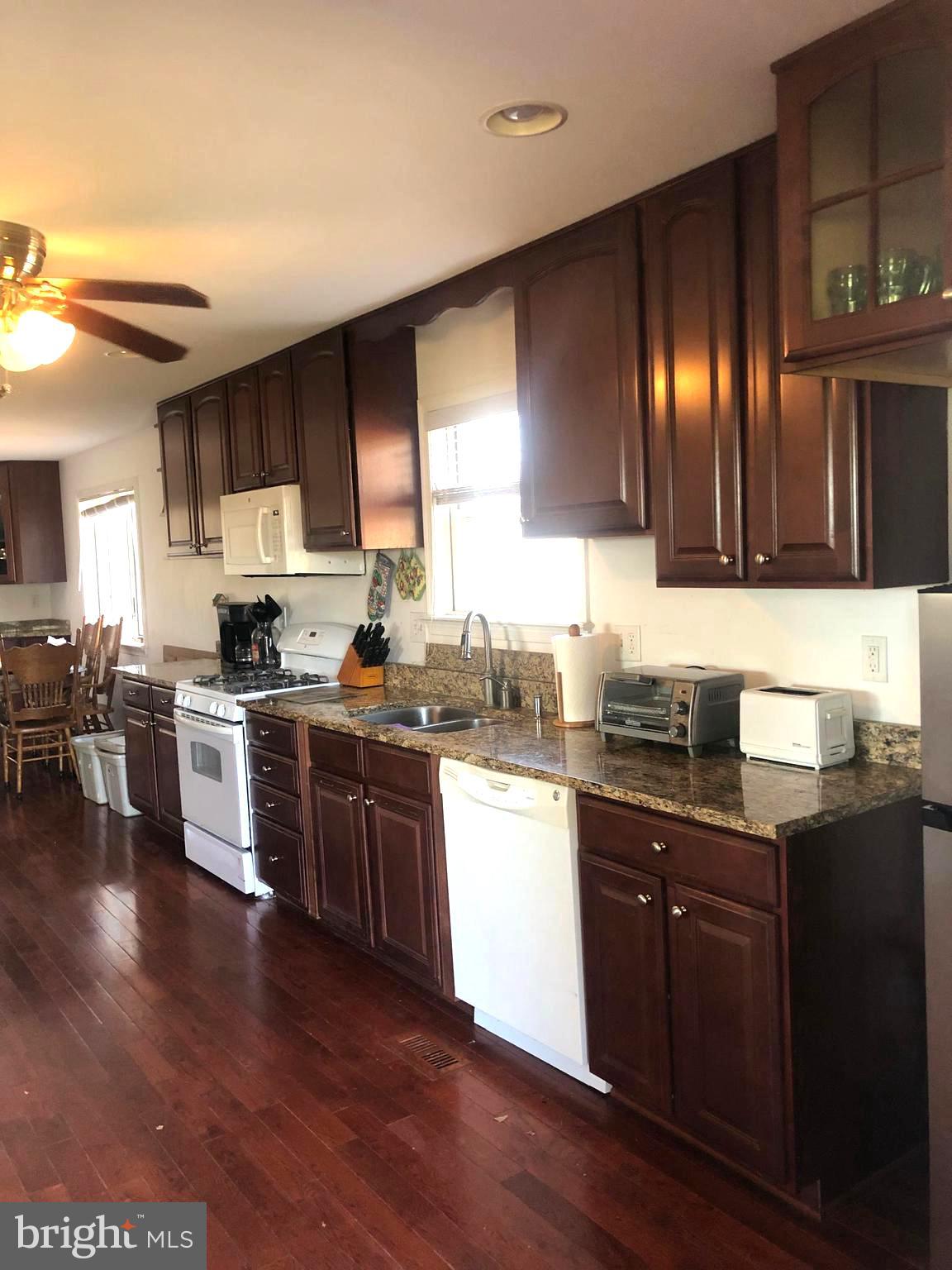 12550 Shoemaker Road Taneytown, MD 21787 - Photo 18 of 53 a kitchen with stainless steel appliances granite countertop wooden cabinets a refrigerator a sink a stove a microwave and wooden floors
