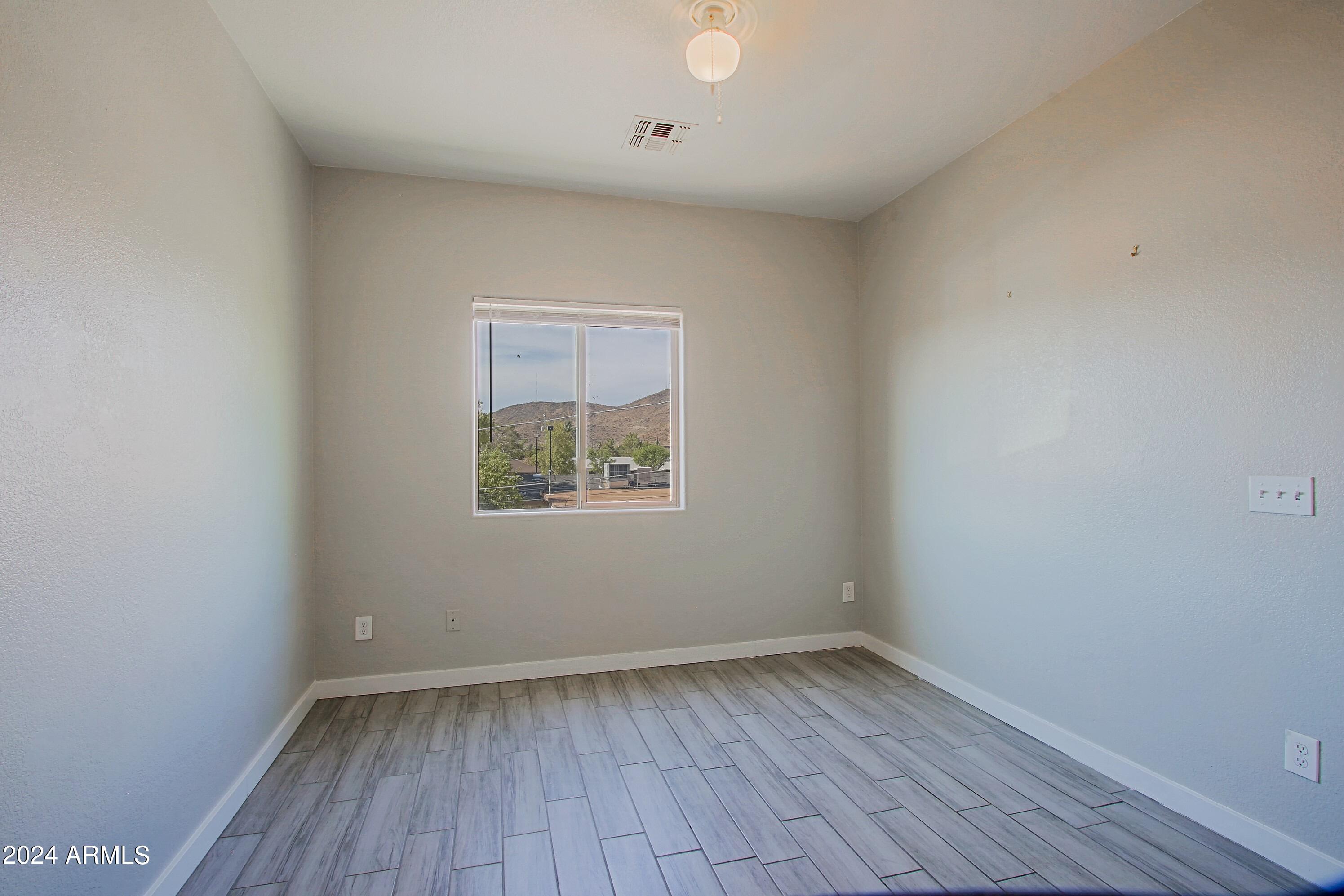 1614 West Purdue Avenue, Unit 102 Phoenix, AZ 85021 - Photo 6 of 11 a view of an empty room with wooden floor and a window