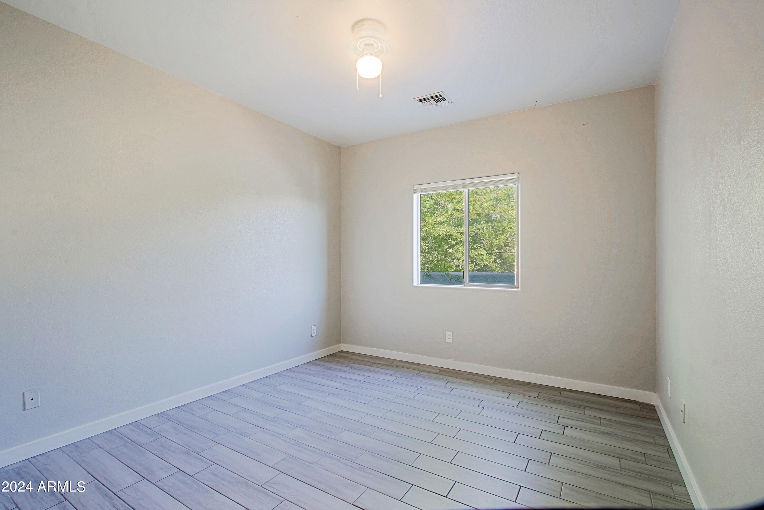 1614 West Purdue Avenue, Unit 102 Phoenix, AZ 85021 - Photo 7 of 11 wooden floor in an empty room with a window