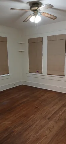 a view of an empty room with wooden floor and chandelier