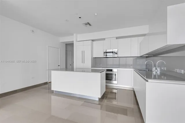 a living room with stainless steel appliances kitchen island granite countertop a sink and cabinets