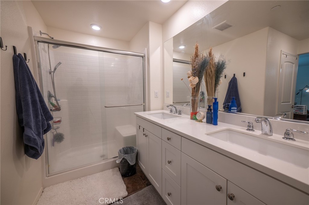 1099 Little Leaf Street Calimesa, CA 92320 - Photo 16 of 32 a bathroom with a double vanity sink a mirror a bathtub and shower
