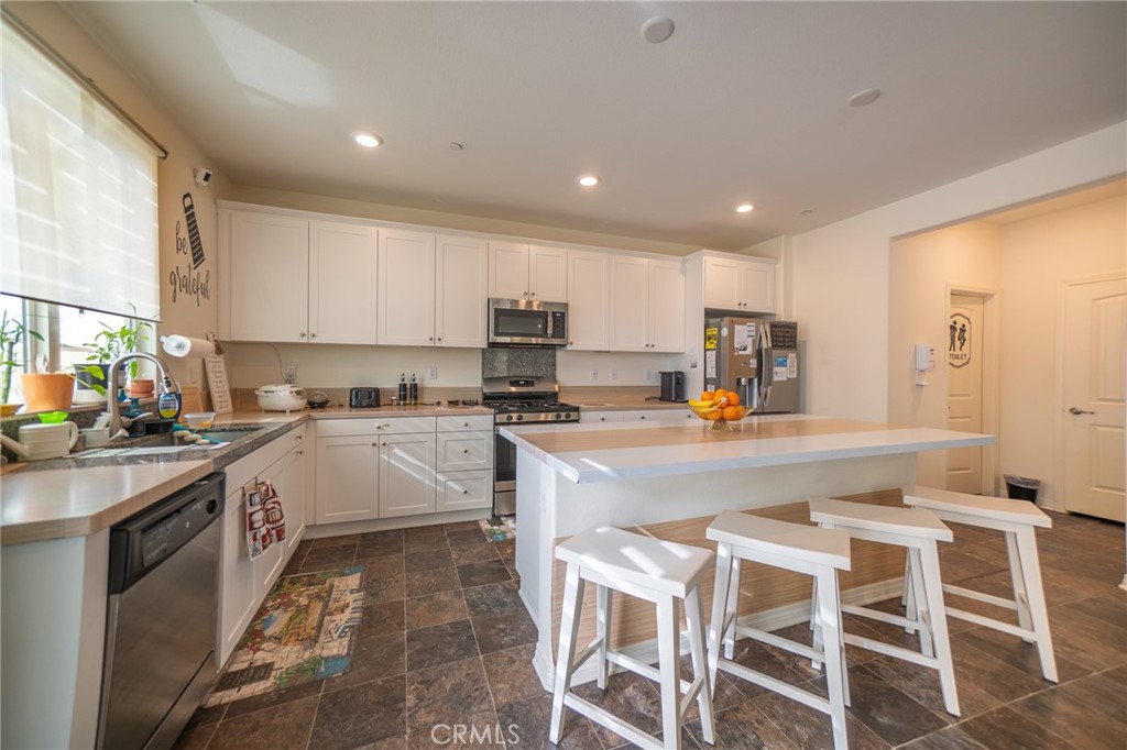 1099 Little Leaf Street Calimesa, CA 92320 - Photo 6 of 32 a kitchen with kitchen island granite countertop wooden cabinets and white appliances